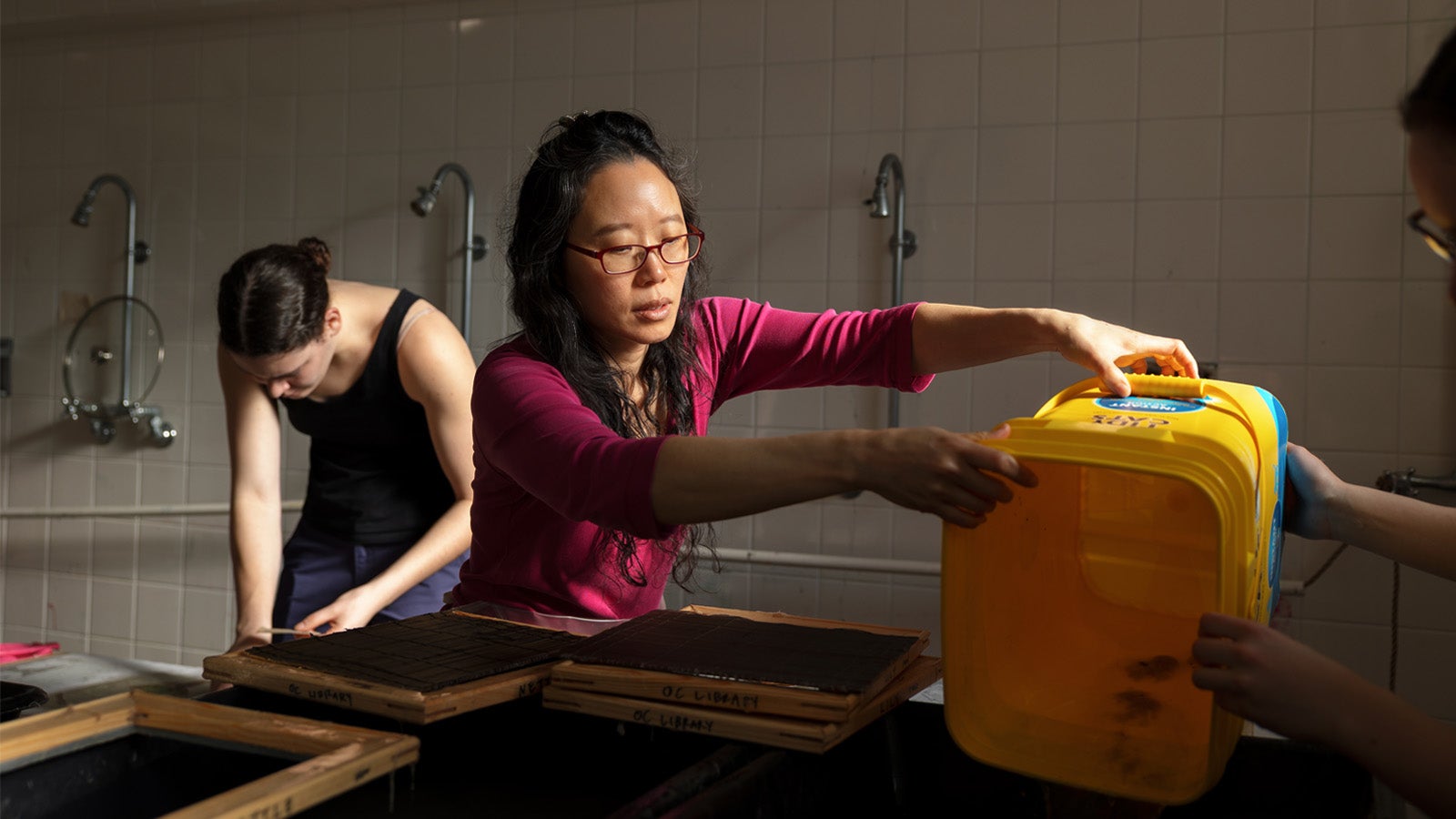 a person in a magenta shirt works making paper
