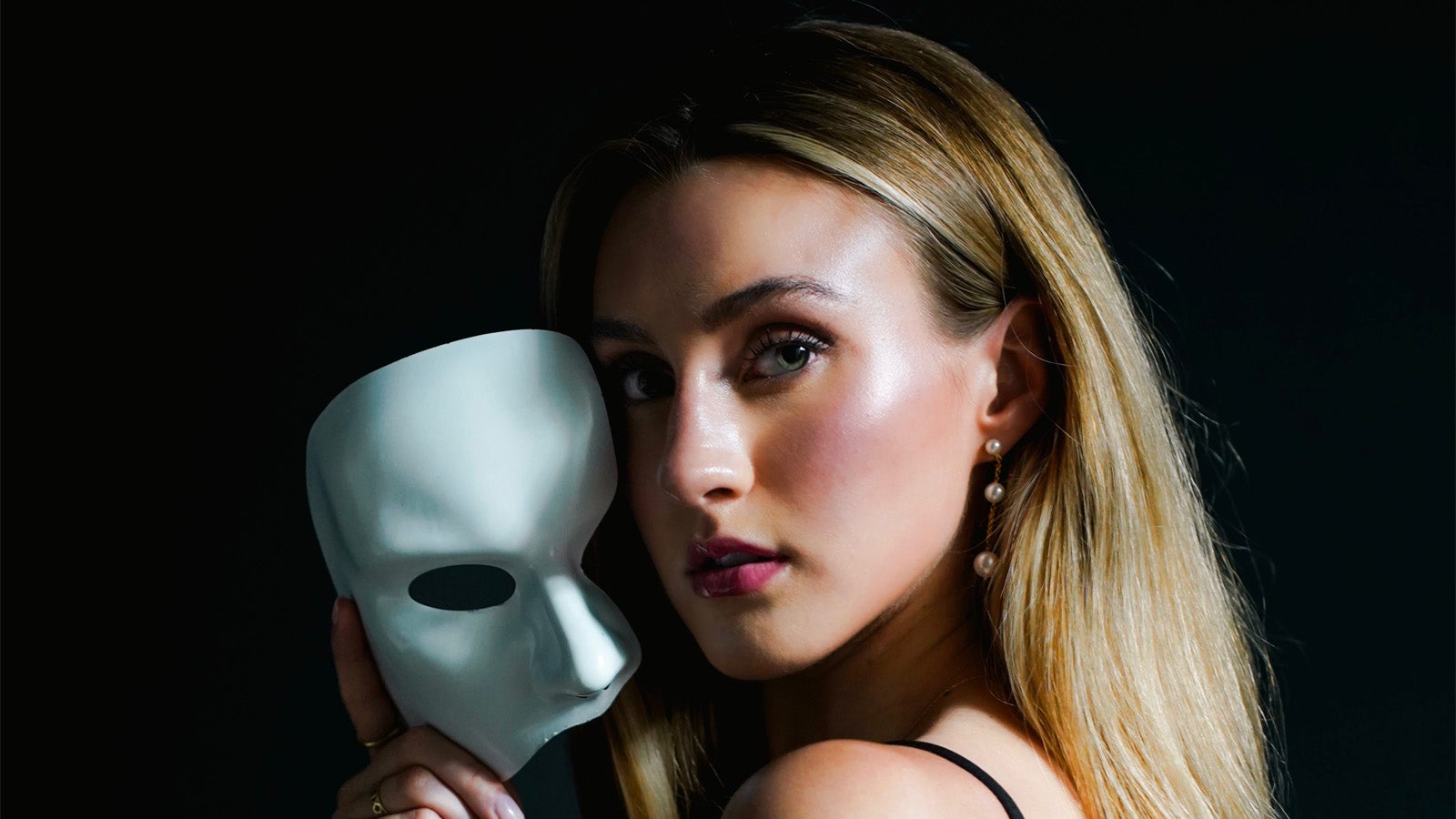 a person holding a phantom mask next to their head