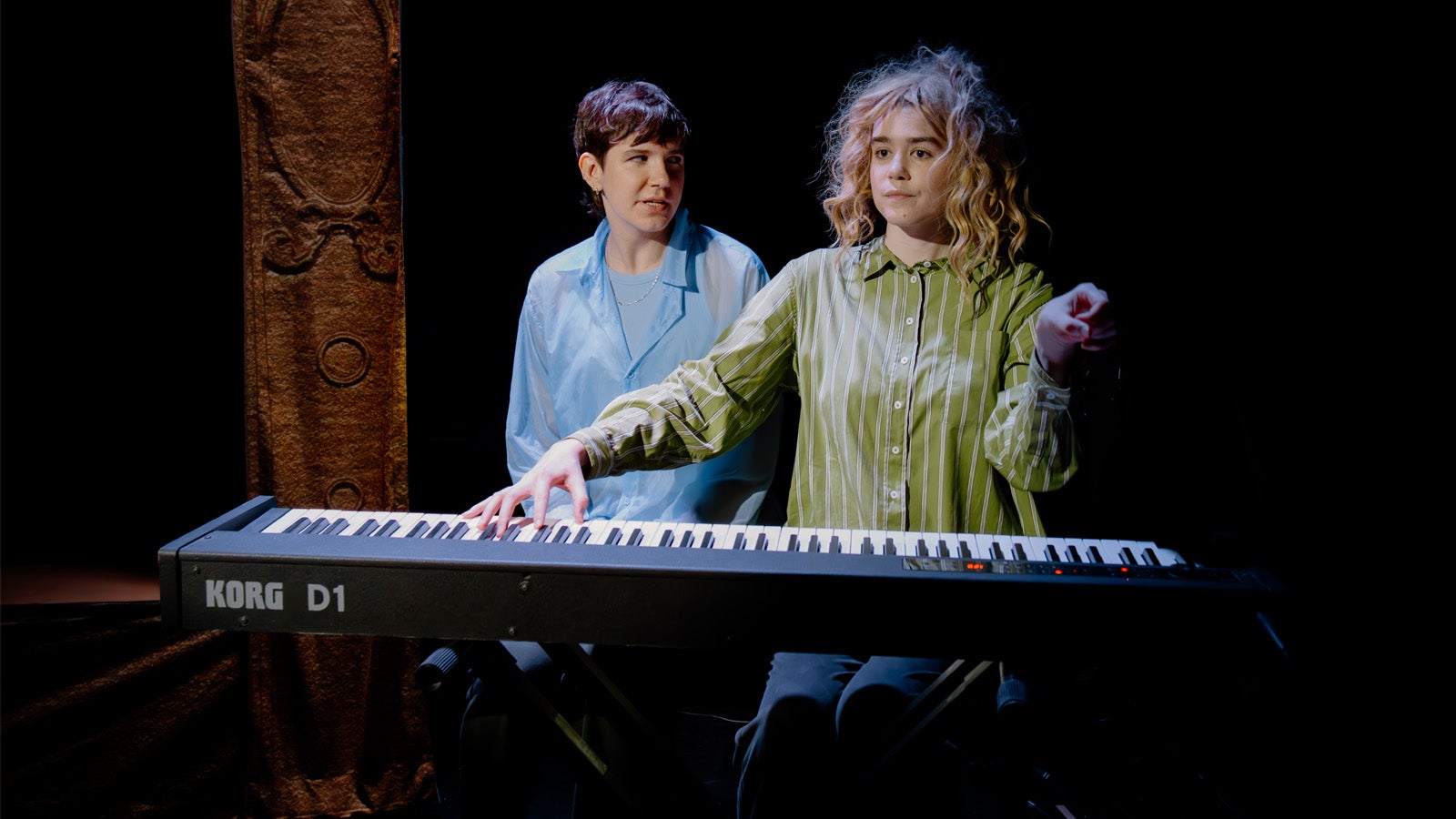 a person wearing a wig and a green top playing a piano
