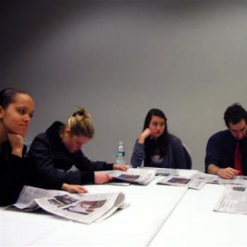 Students around a table examining newspapers