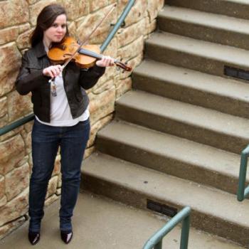 Allison plays her violin by a stone and concrete staircase