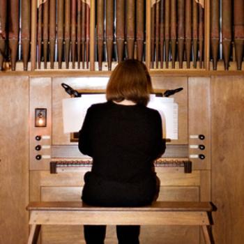 A woman plays a pipe organ