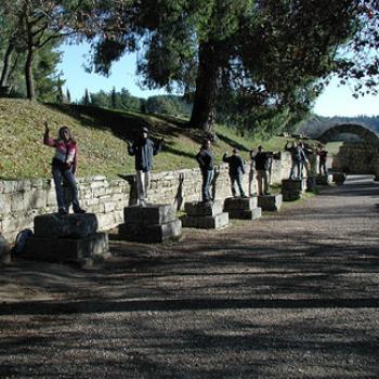 Students pose as statues by a stone wall