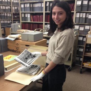 Eva wears gloves while handling photographs in a file room
