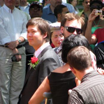 Young man in a crowd wearing a boutonnière on his suit jacket