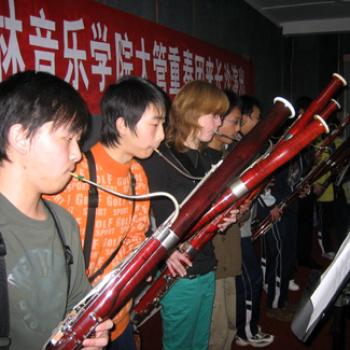 A row of bassoonists performs under a banner with Chinese characters