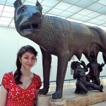 Lauren by a bronze sculpture of a wolf suckling two human infants