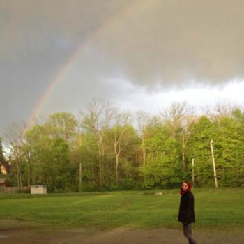 Lena stands under a rainbow