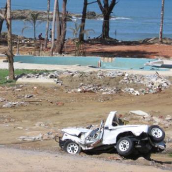 A mangled jeep and other debris by a beach.