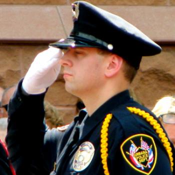 Matt salutes. He is wearing the dress uniform of the Urbana Police Department.