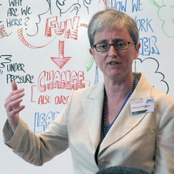 Nancy speaks in front of a whiteboard with phrases including Fun → Change, under pressure, why are we here?