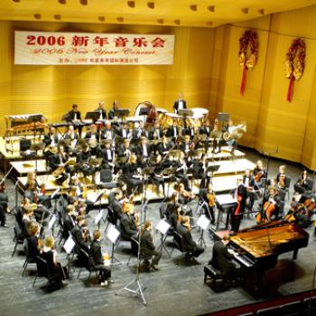 An orchestra on stage under a banner with Chinese characters and '2006 New Year Concert'.
