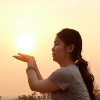 Qian extends her palms as if she's holding the sun.
