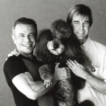Robert and his spouse Steven pose with a fluffy poodle.