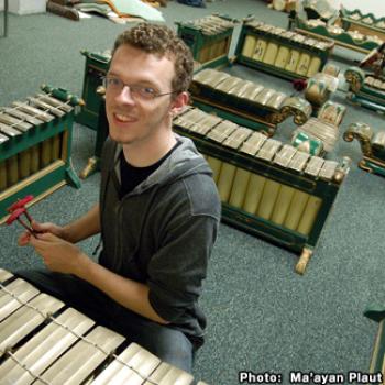 Sean is positioned at one section of a sprawling Gamelan. Many of the pieces resemble xylophones.
