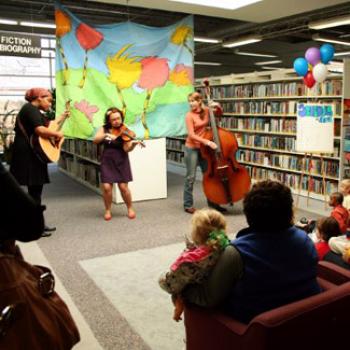 A trio plays music in the children's section of the public library.