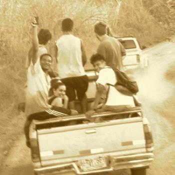 Group of people riding in the back of a pickup truck.
