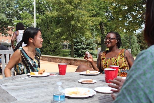 Students at a patio table outside the Afrikan Heritage House.