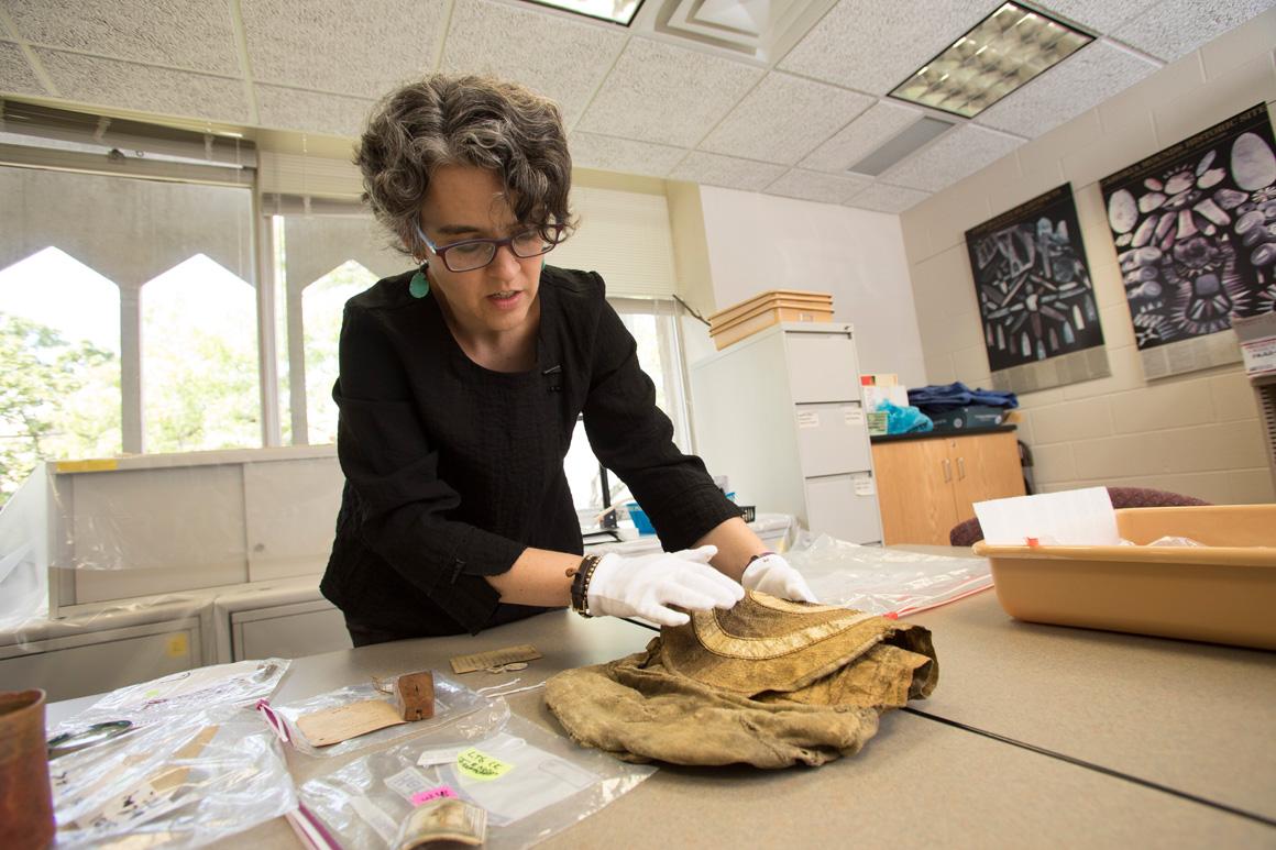 A professor handles an artifact with white gloves.