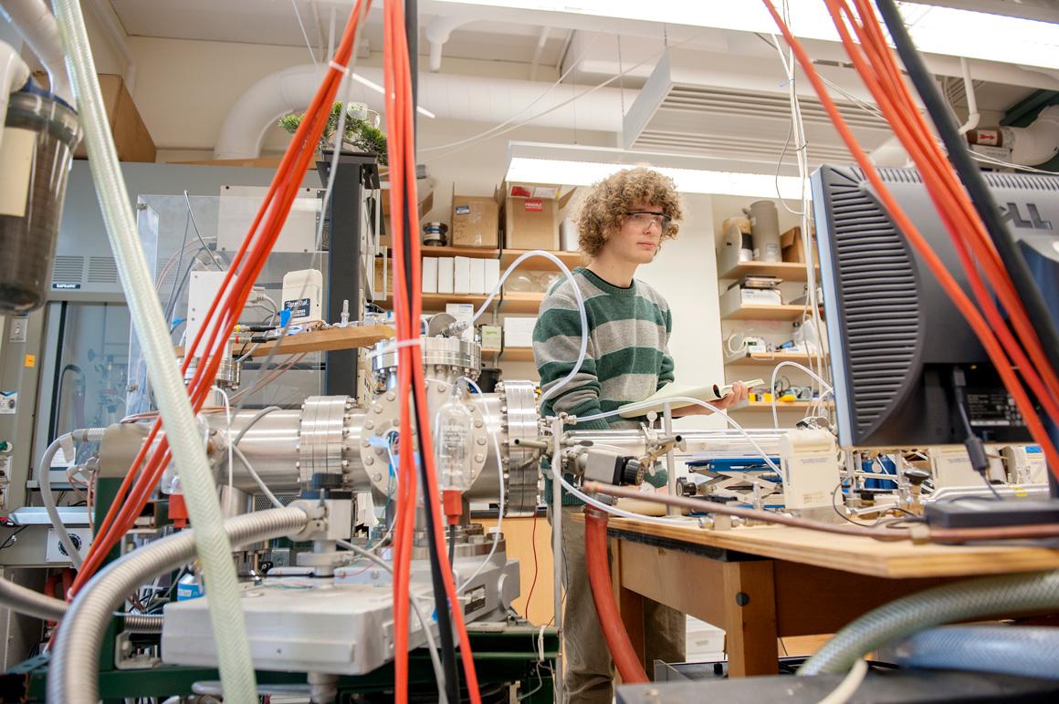 A student surrounded by lab equipment.