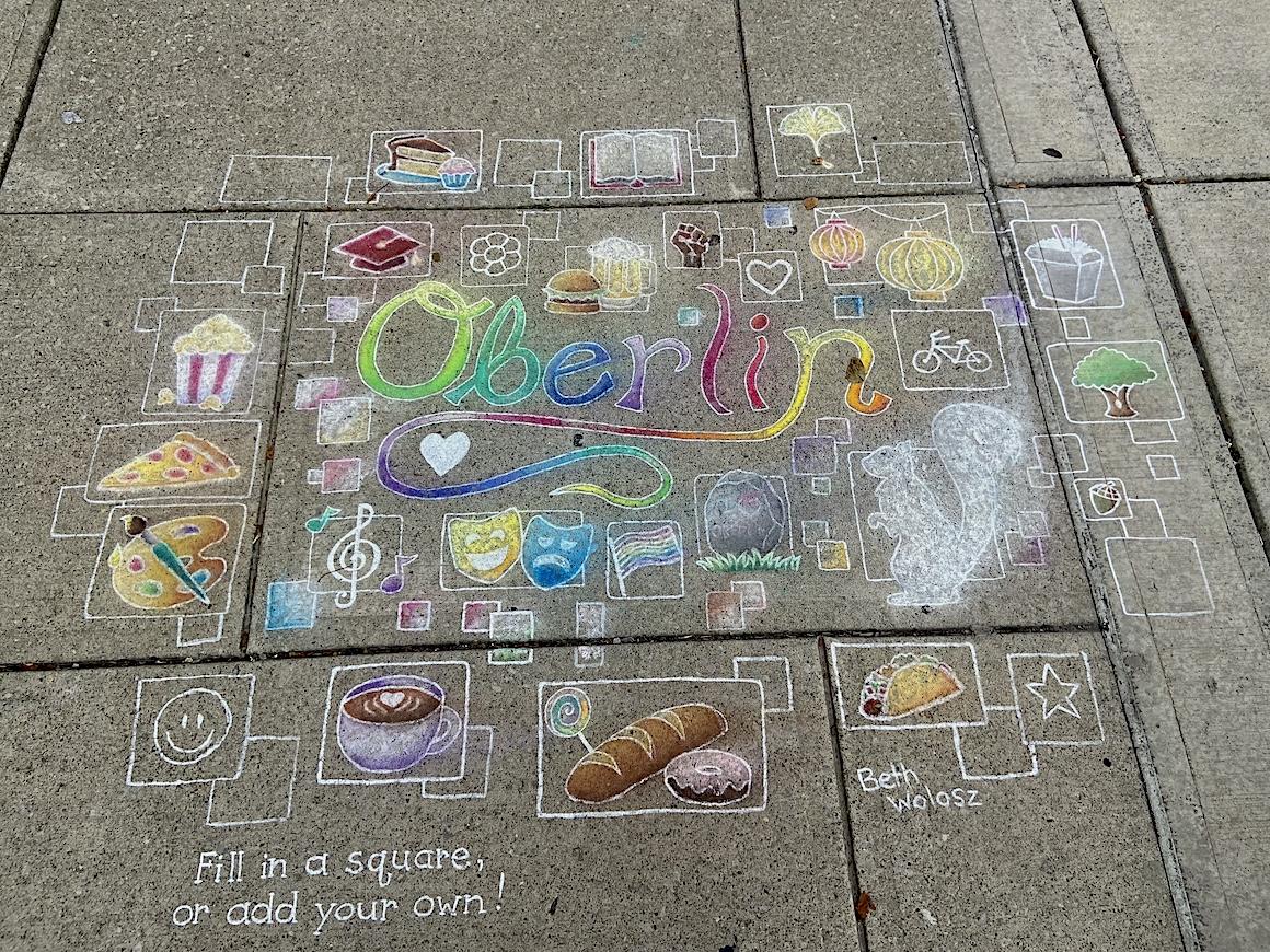 A chalk drawing on a sidewalk has many pictures surrounding the word Oberlin. They depict a squirrel, Chinese lanterns, a bicycle, some baked goods, and a musical G clef.