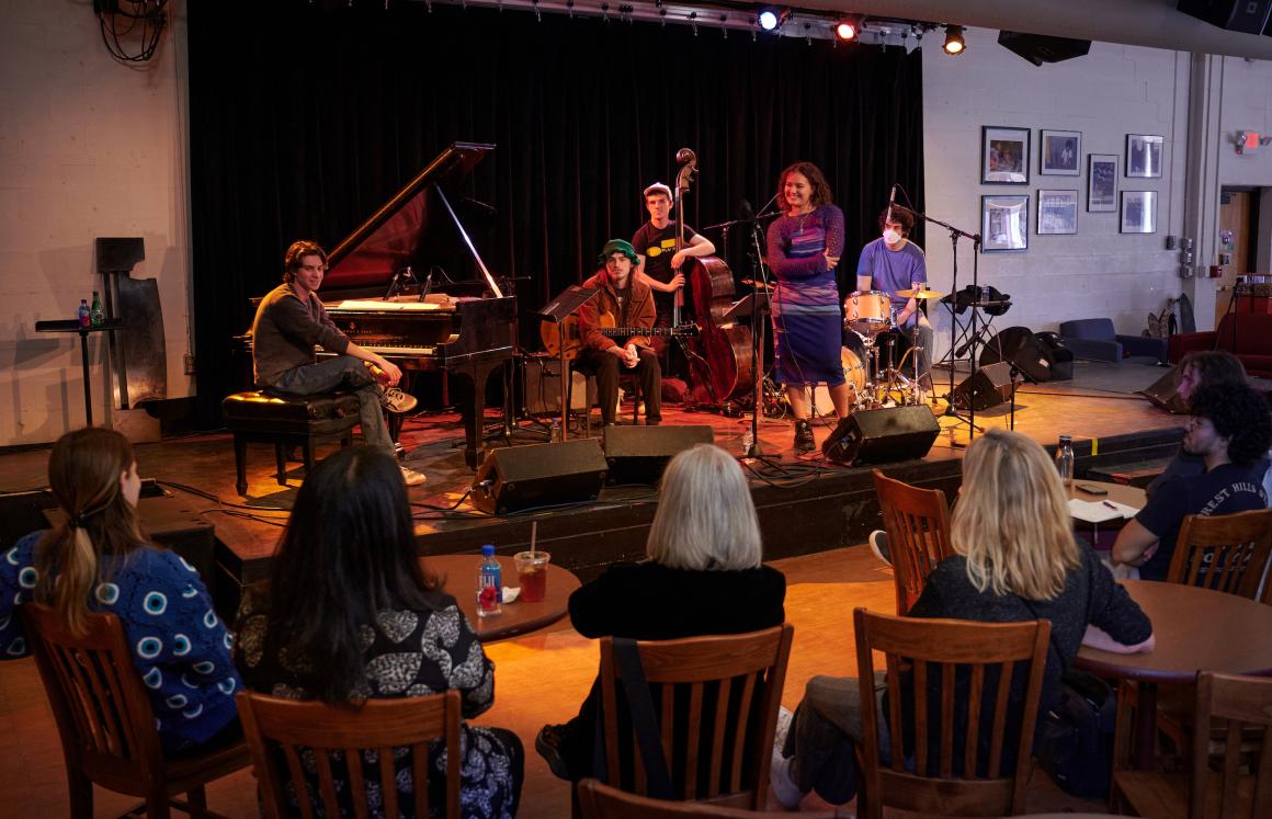 student jazz group sits on stage and receives feedback from Artemis members