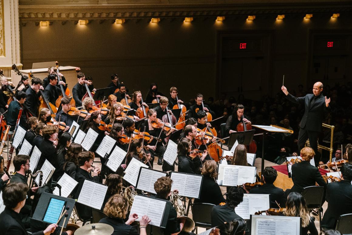 Conductor leading orchestral musicians in a performance.