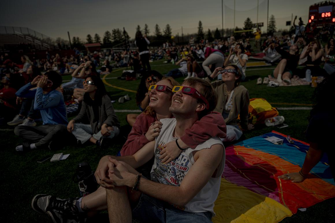 A man and a woman embracing while watching the solar eclipse.