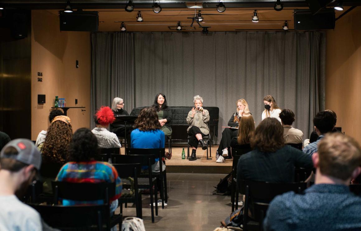 five women sit on stage in front of audience of students for panel discussion 