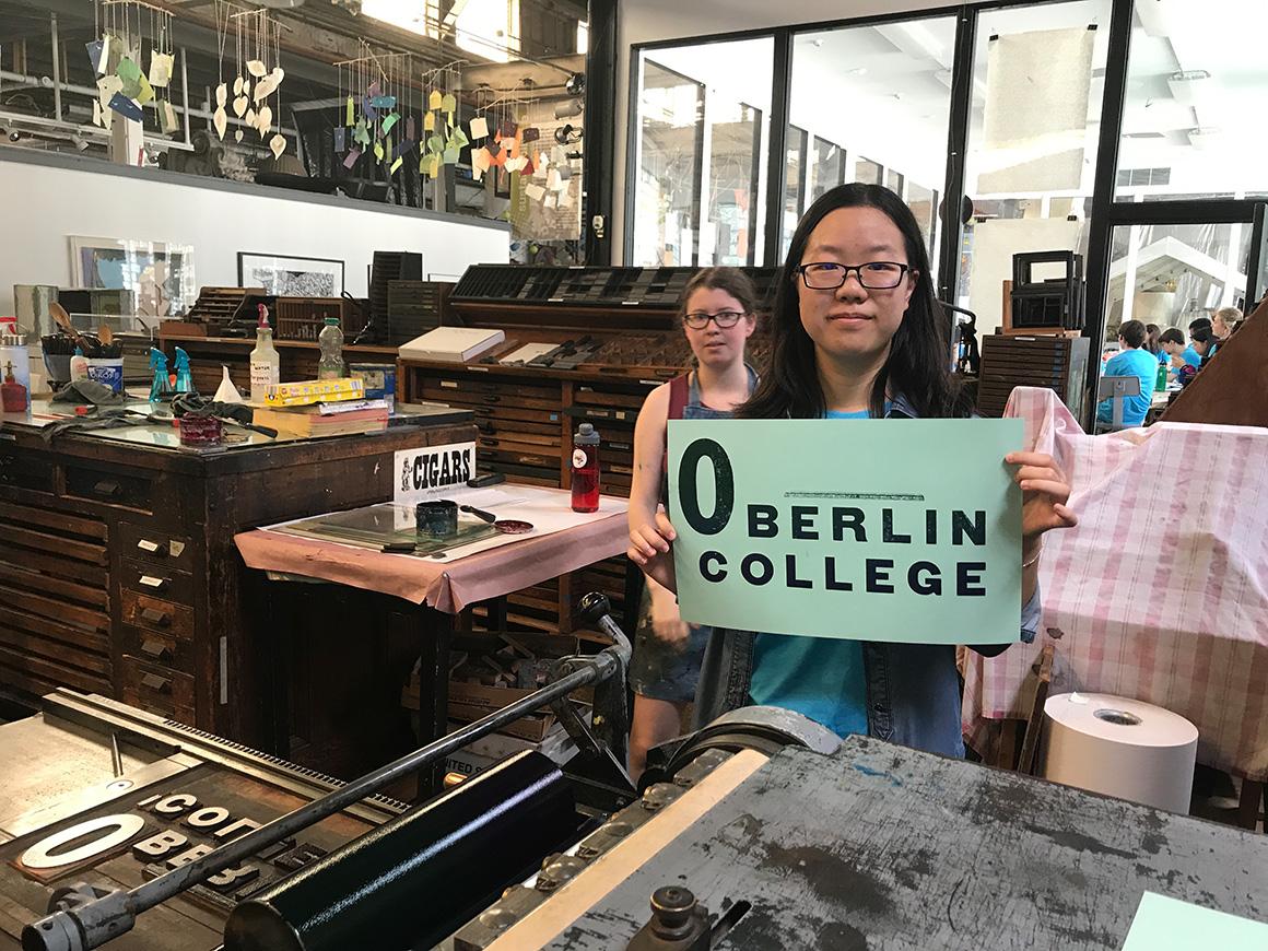 A student holds up a sign she has printed. It says Oberlin College.