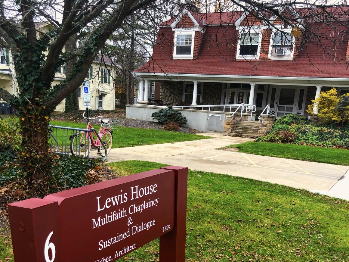 Photograph of Lewis House from the front, showing pink bike at bike rack and sign reading "Multifaith Chaplaincy & Sustained Dialogue"