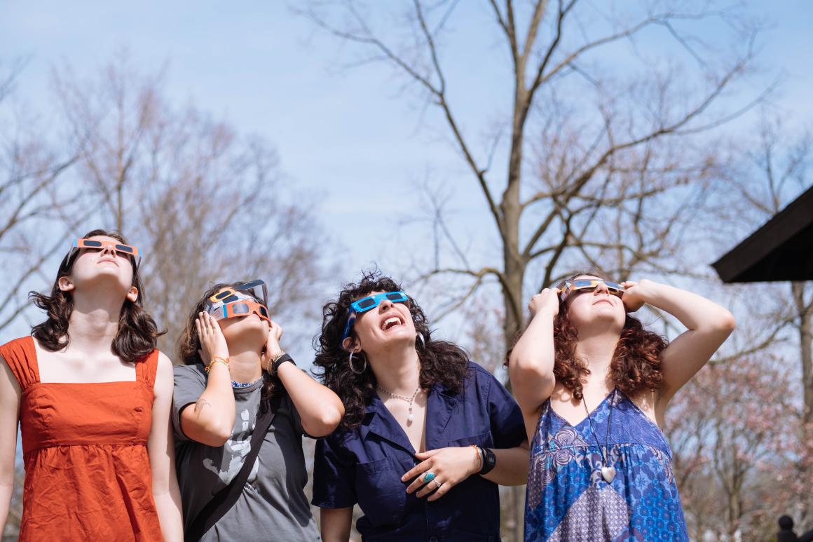 Four girls watching the solar eclipse through eclipse glasses.