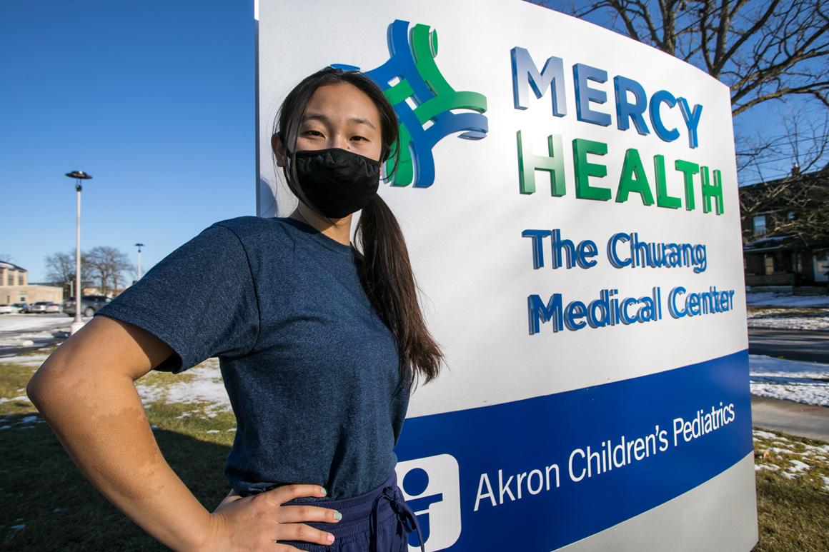 A student poses by the building sign for Mercy Health Chuang Medical Center.