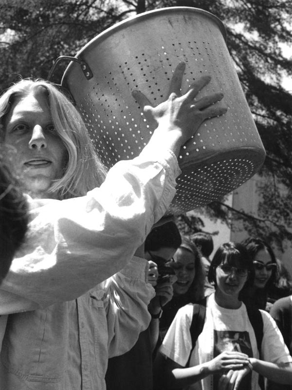 Black and white photo of student holding colander to see the shadow of an annular eclipse