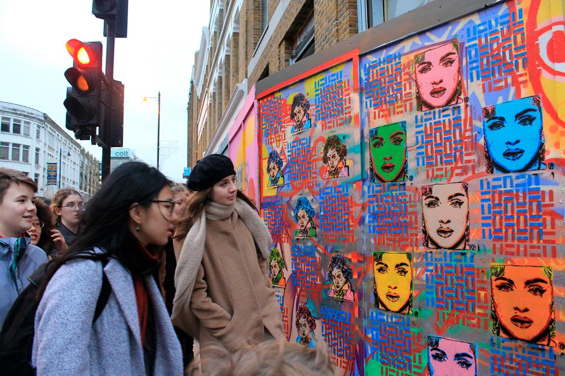 On a busy street corner, people look at an art installation.
