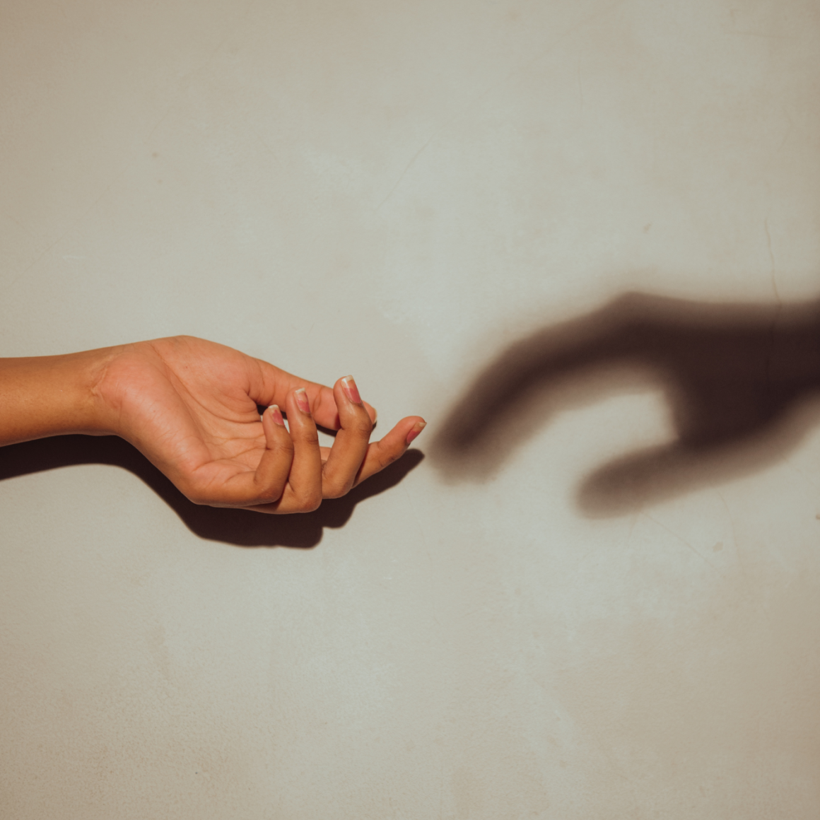 A hand reaching out to a shadow of a hand
