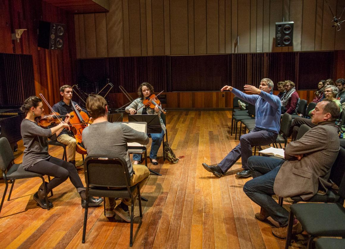String players seated in a circle receiving instruction.