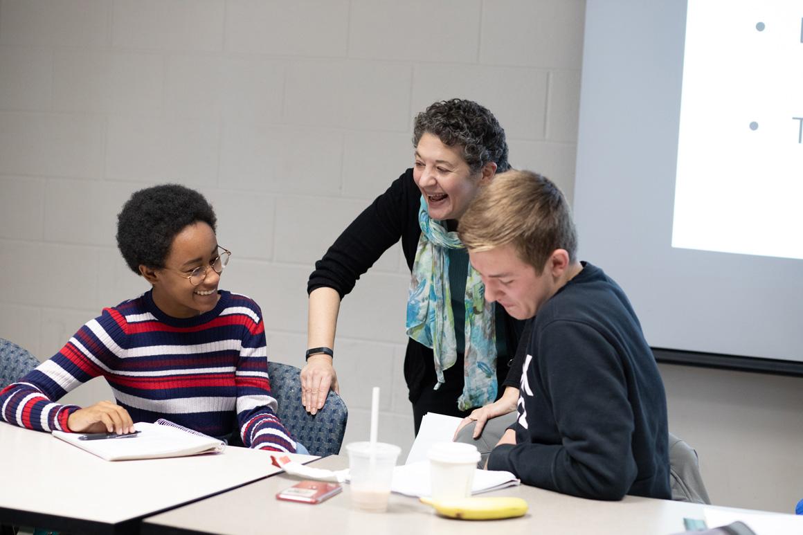 A professor shares a laugh with students during class.