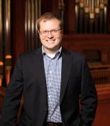 David Kazimir standing in dark suit and checkered shirt