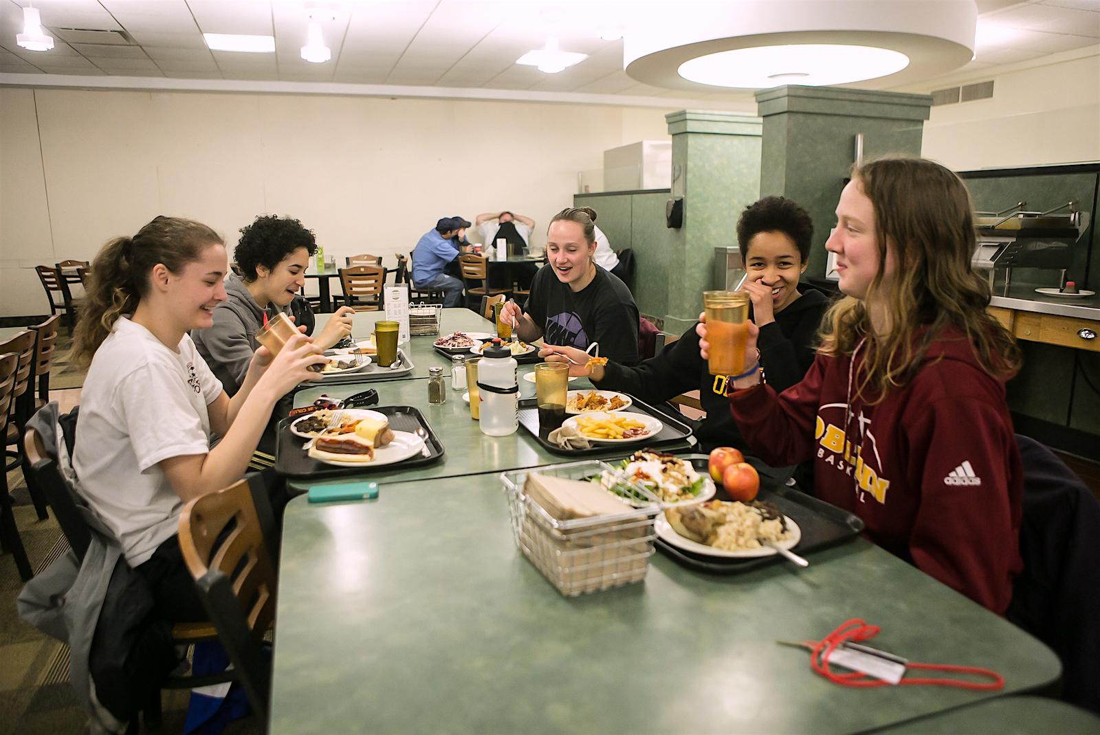 A group of friends enjoys a meal at a dining hall table