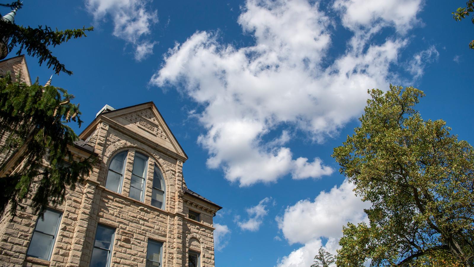 A blue sky with puffy clouds above Peters Hall.