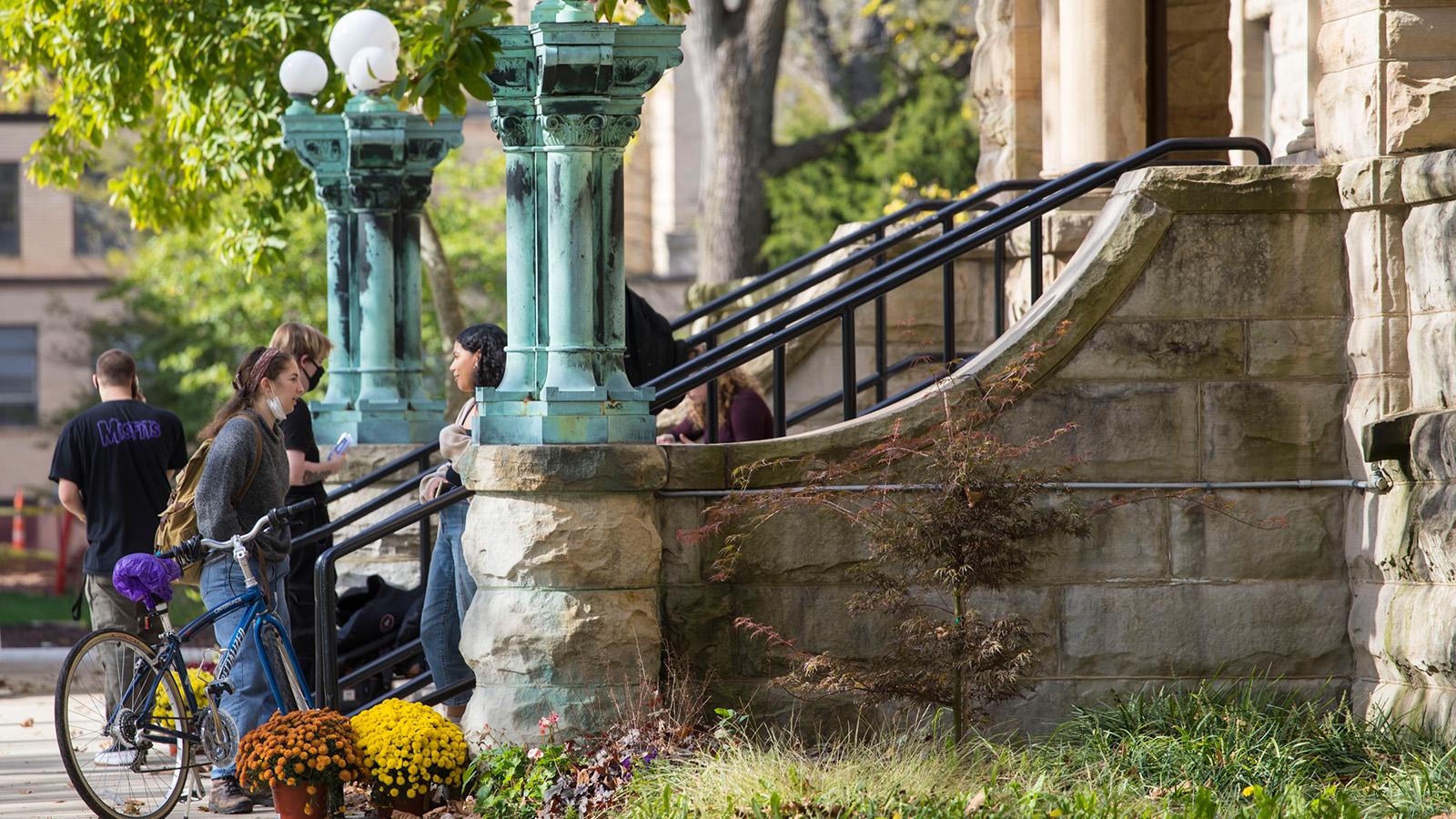 Students have casual conversations on the stone steps of Wilder Hall.
