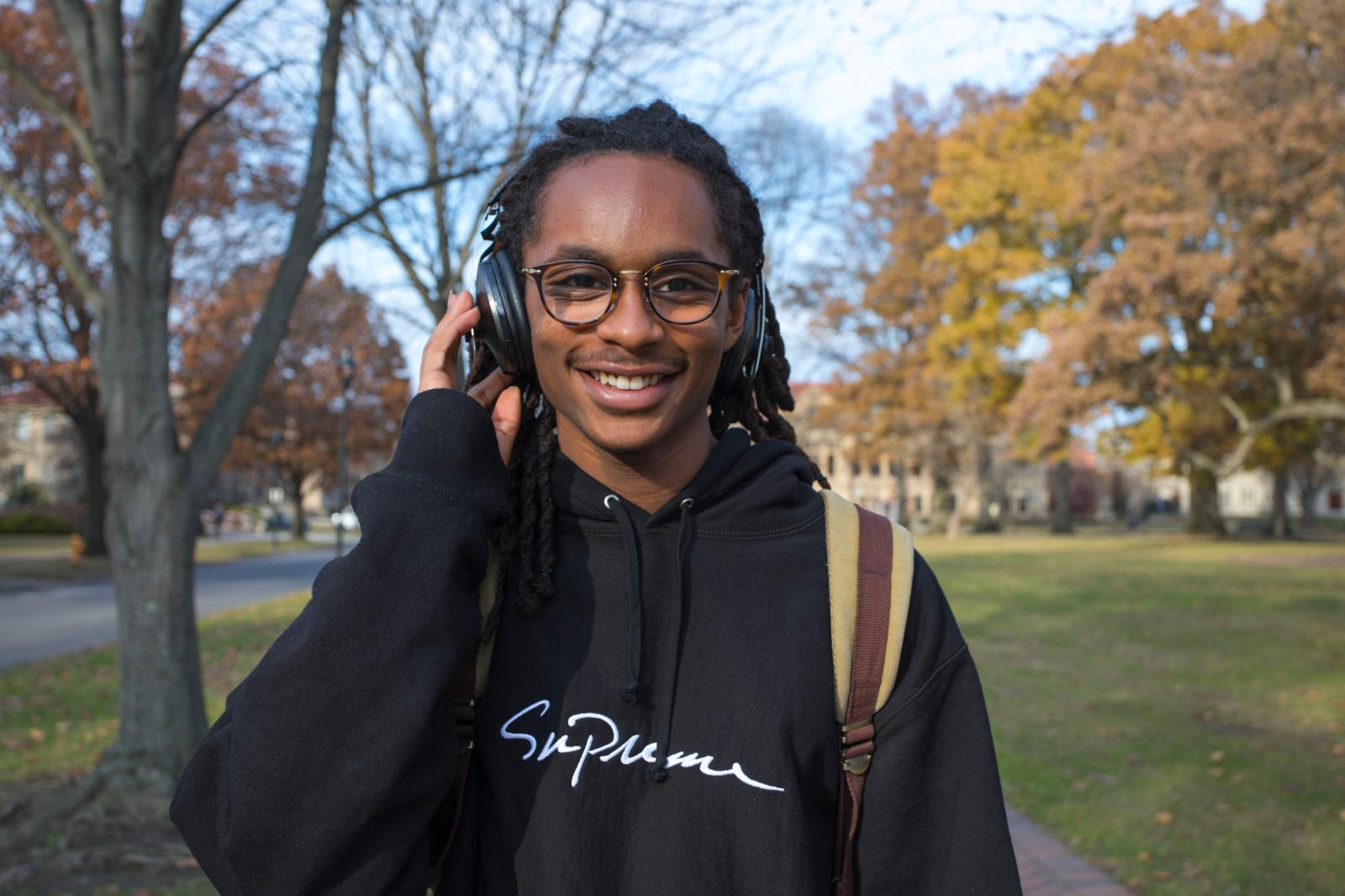 Student wearing headphones, outdoors in fall.