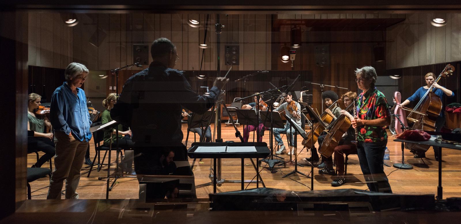 A string ensemble and oboist in the recording studio, as seen through the control room glass. 