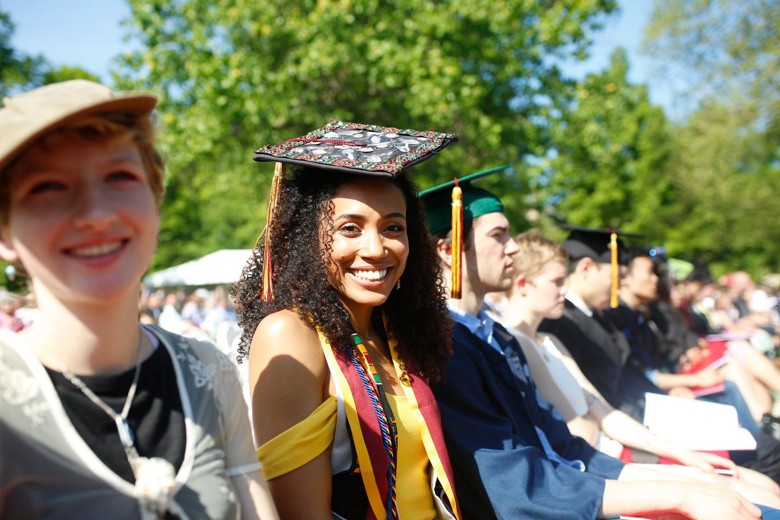 A smiling student in cap and gown at graduation.