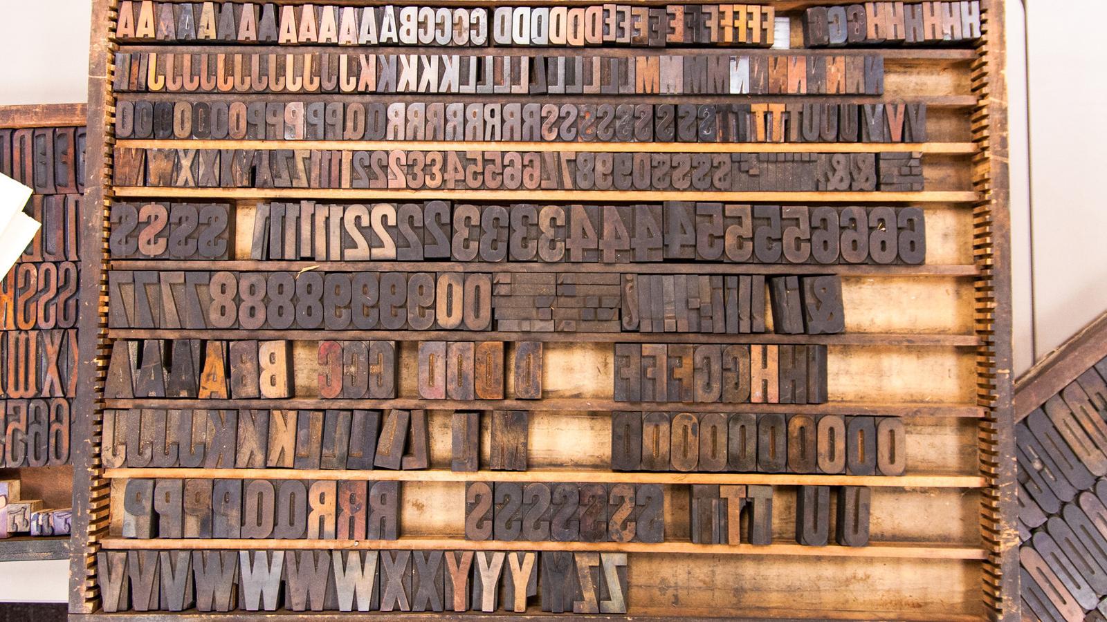 Letters of a letterpress arranged on a shelf.