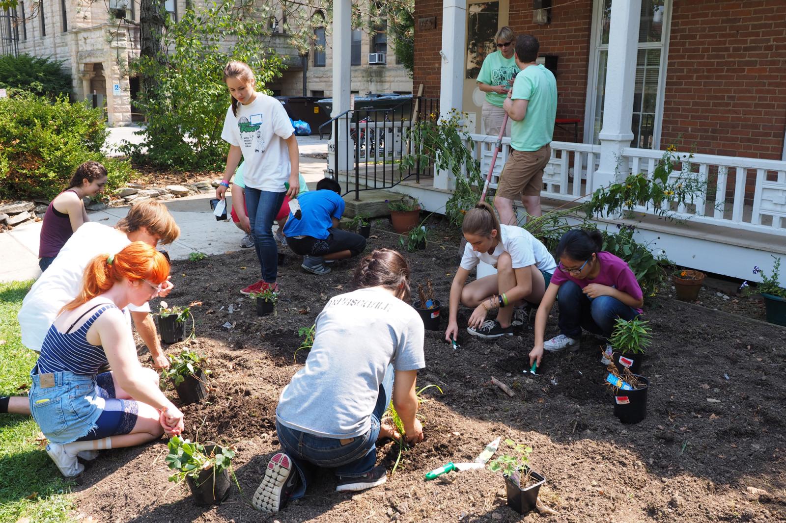 A group of students plants a garden in front of a house.