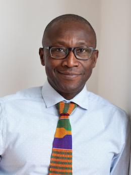 Darko Opoku in white shirt with kente colored tie.