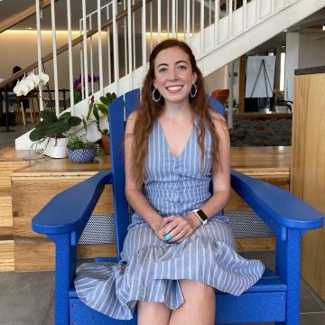 A red-headed female student sitting in a blue chair.