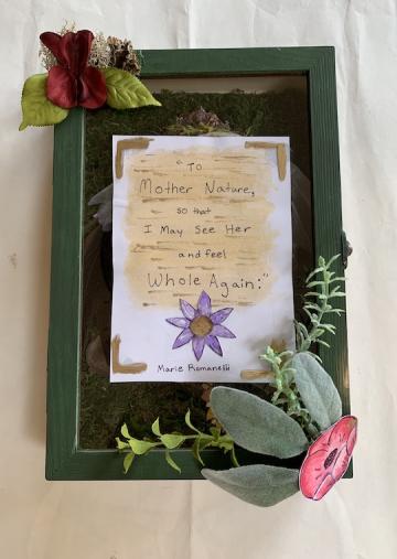 A wooden box framed in glass and flowers.